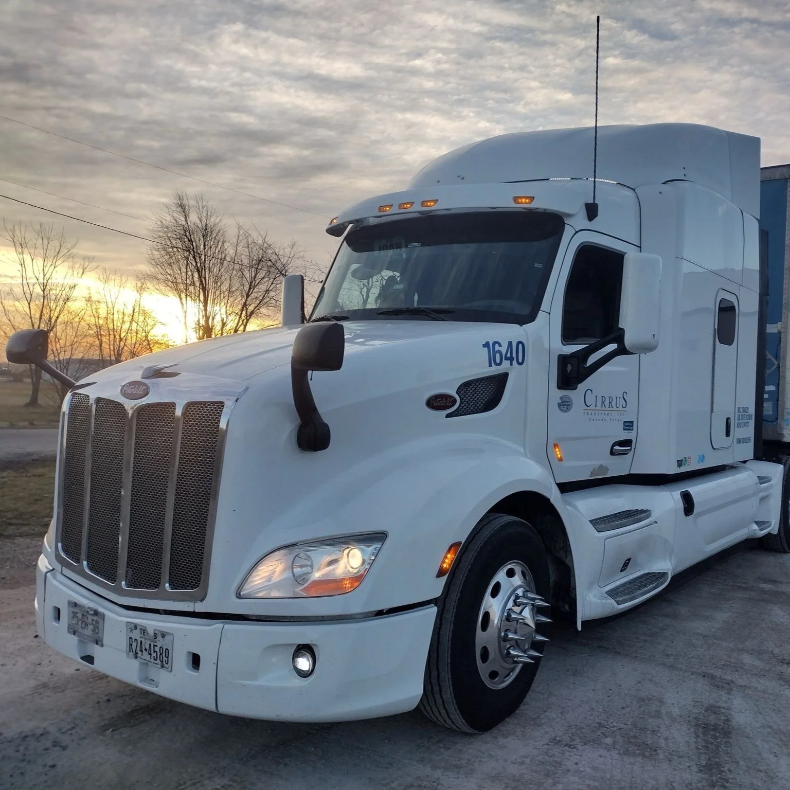 A white semi-truck with the number 1640, branded Cirrus Transport, parked outdoors during sunset with trees and a cloudy sky in the background.