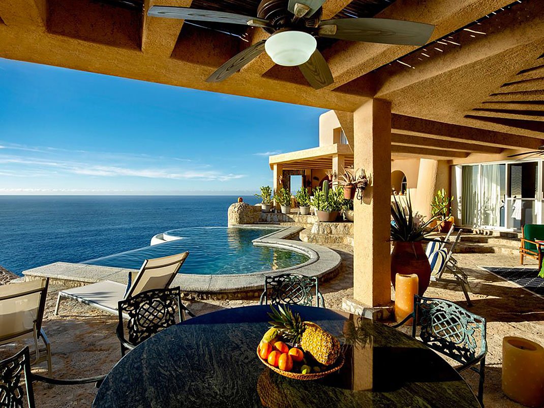 Luxury outdoor patio with pool, ocean view, and fruit on table