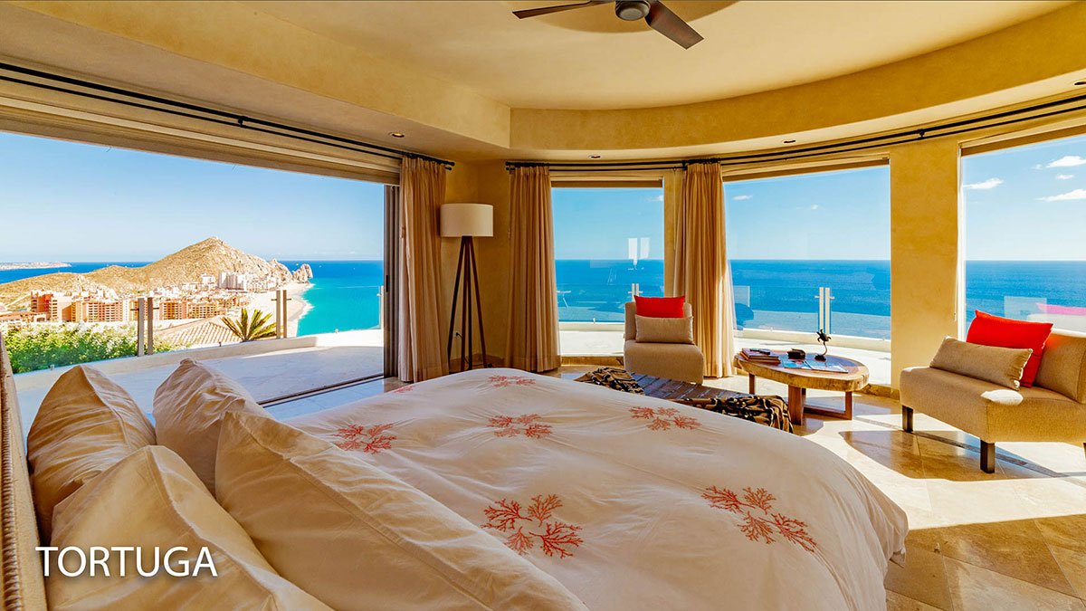 Luxury bedroom with ocean view, large windows, modern furniture, and "TORTUGA" text in the corner.