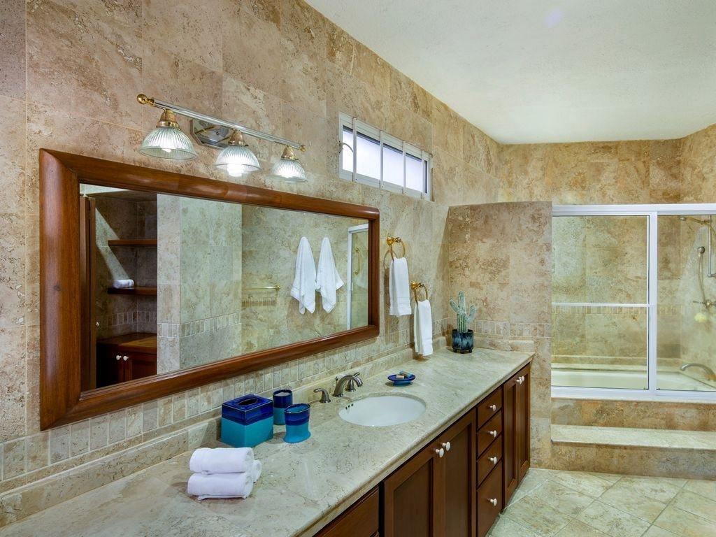 Luxurious bathroom with marble countertops, large mirror, towel rack, decorative lighting, and a glass-enclosed shower.