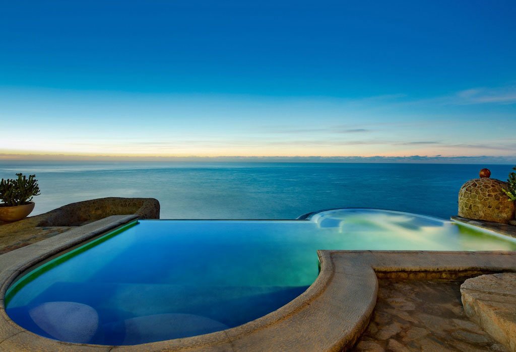 Infinity pool overlooking ocean at sunset with clear sky