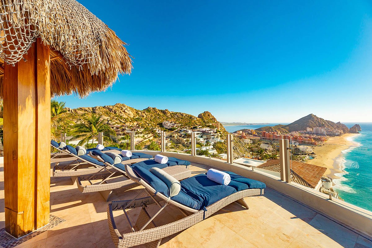 Rooftop patio with lounge chairs, towels, palapa roof, ocean view, and sandy beaches.