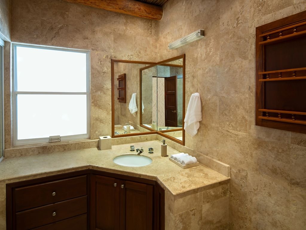 Modern bathroom with marble countertops, large mirror, wooden cabinets, and a towel hanging on the wall.