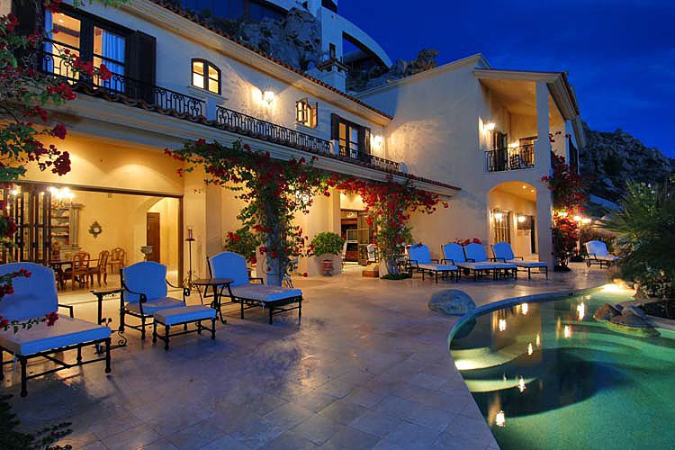 Luxurious villa with pool at dusk, featuring elegant architecture, outdoor seating, illuminated pool, and decorative plants.