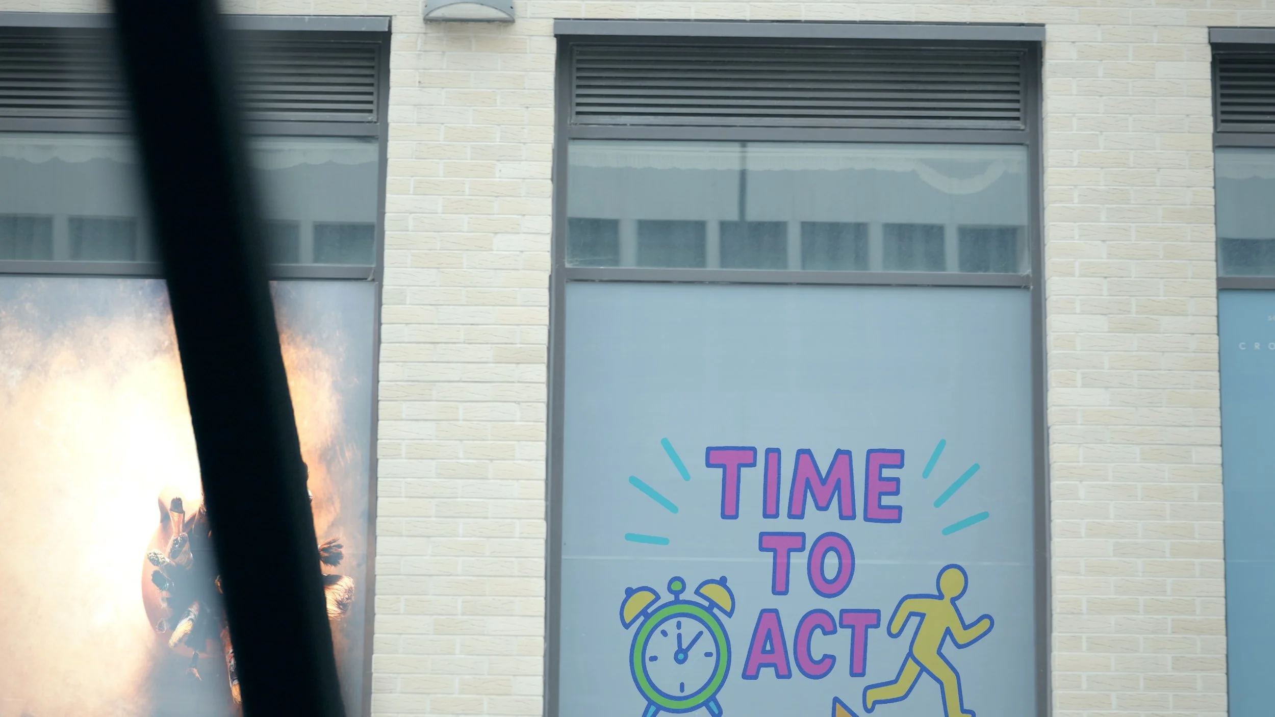 A window with a colorful sign that says 'Time to Act' with a clock and a running person icon.