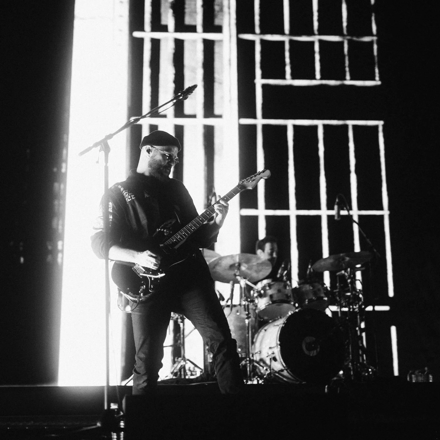 Christian Heidenbauer on stage with electric guitar in front of a lit set