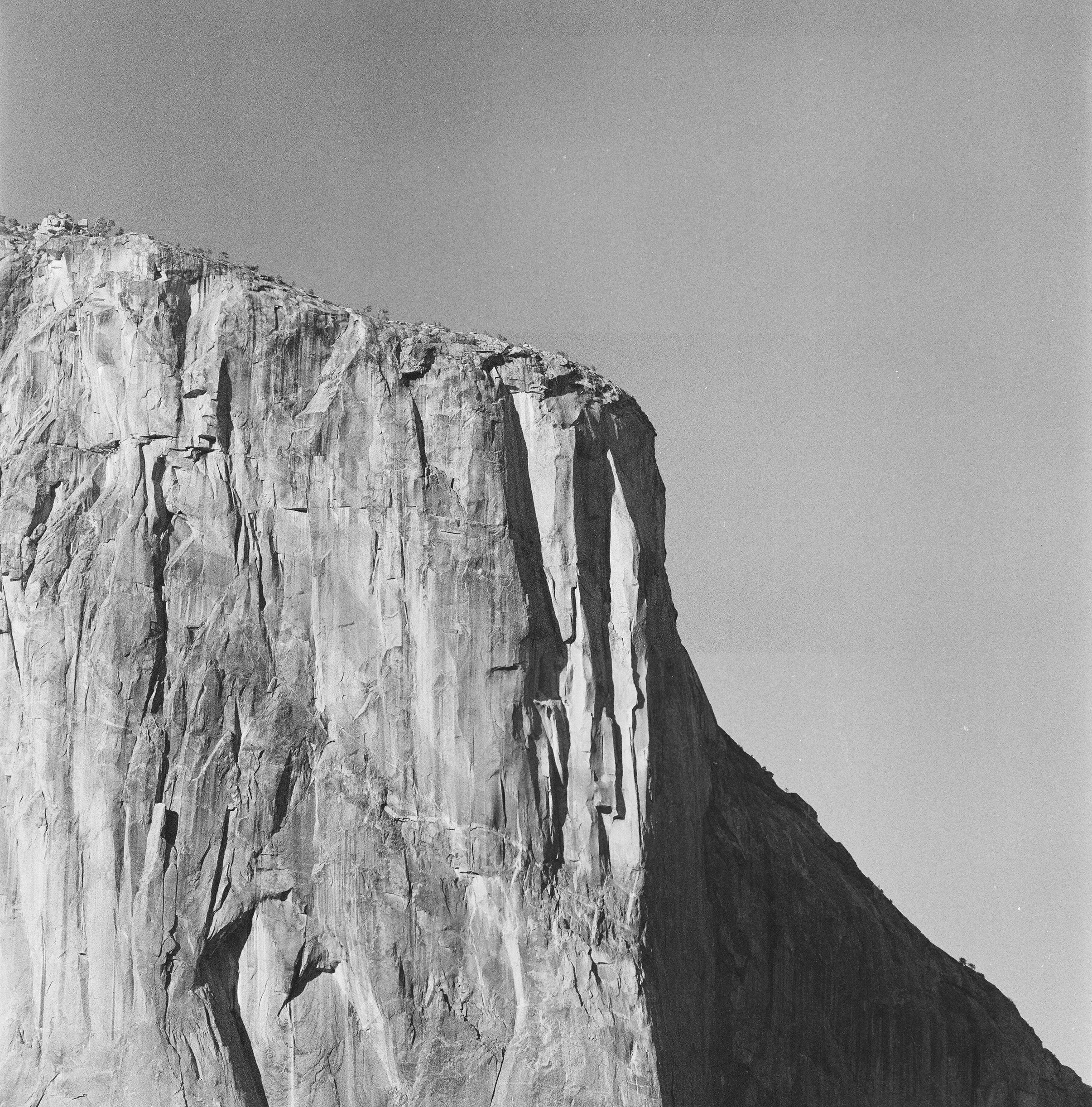 Black and white photo of a sheer granite cliff face, resembling El Capitan in Yosemite.