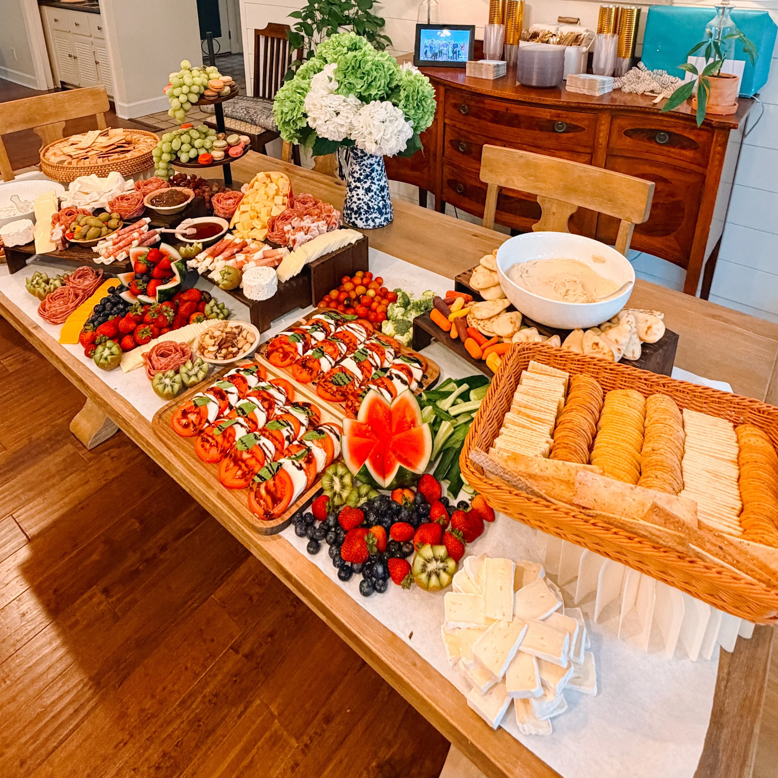 Grazing table with cheeses, cured meats, fresh fruit, caprese, vegetables, dips and breads.