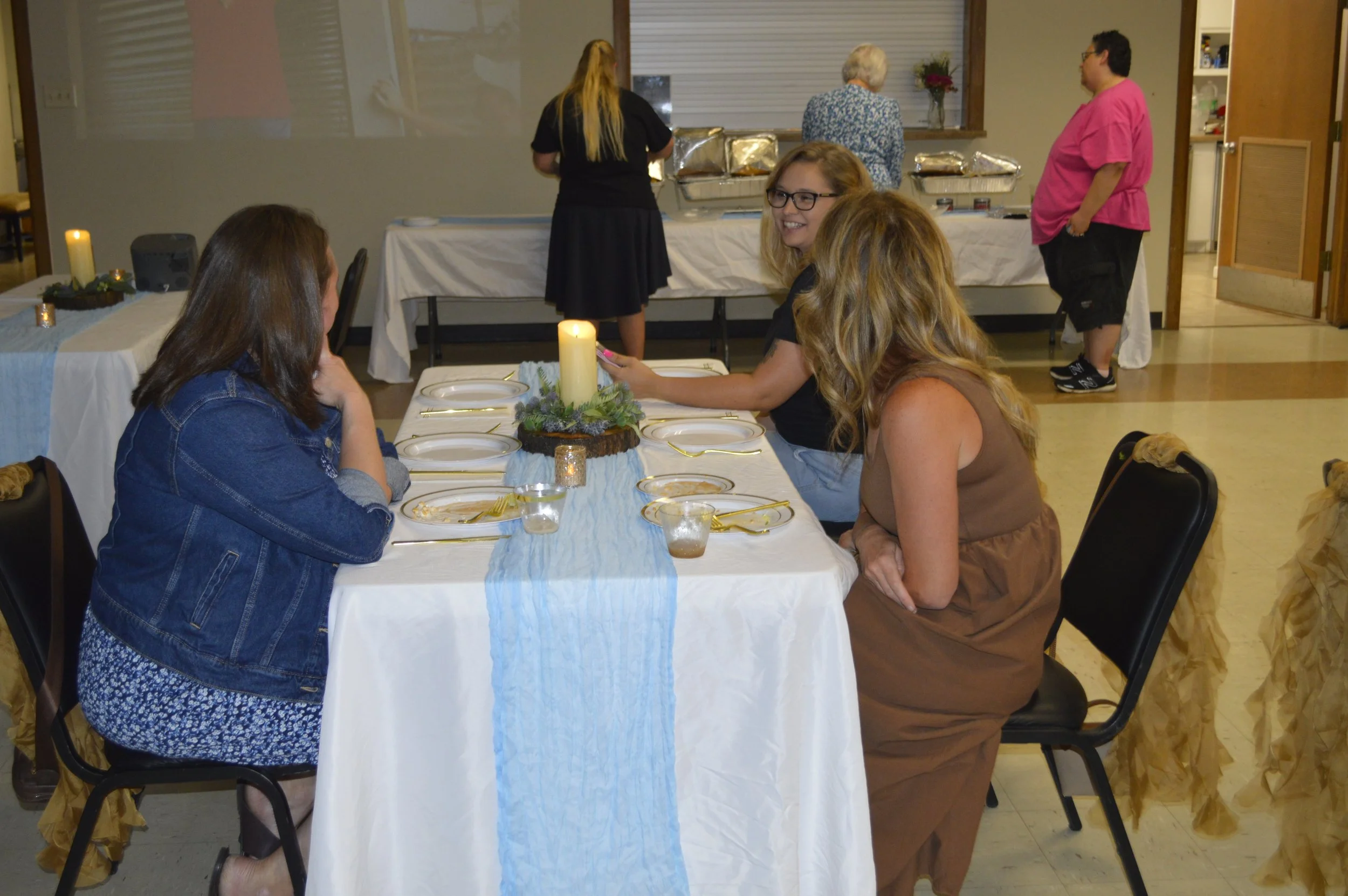 Guatemala fundraiser event with guests seated at decorated tables, a buffet line in the background, and a photo slideshow projected on the wall.