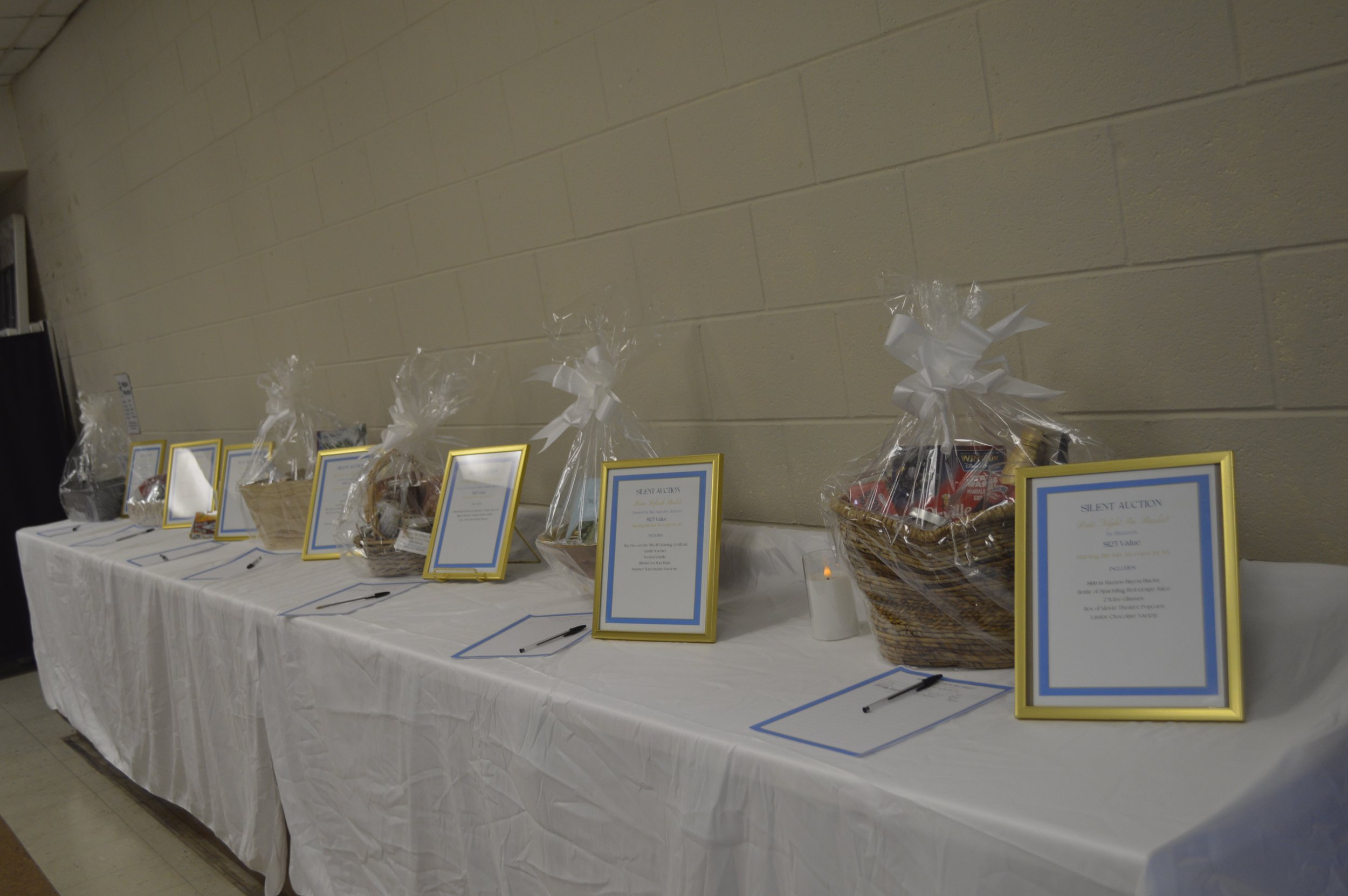 Guatemala fundraiser raffle table with themed gift baskets, bidding sheets, and silent auction items arranged for guests.