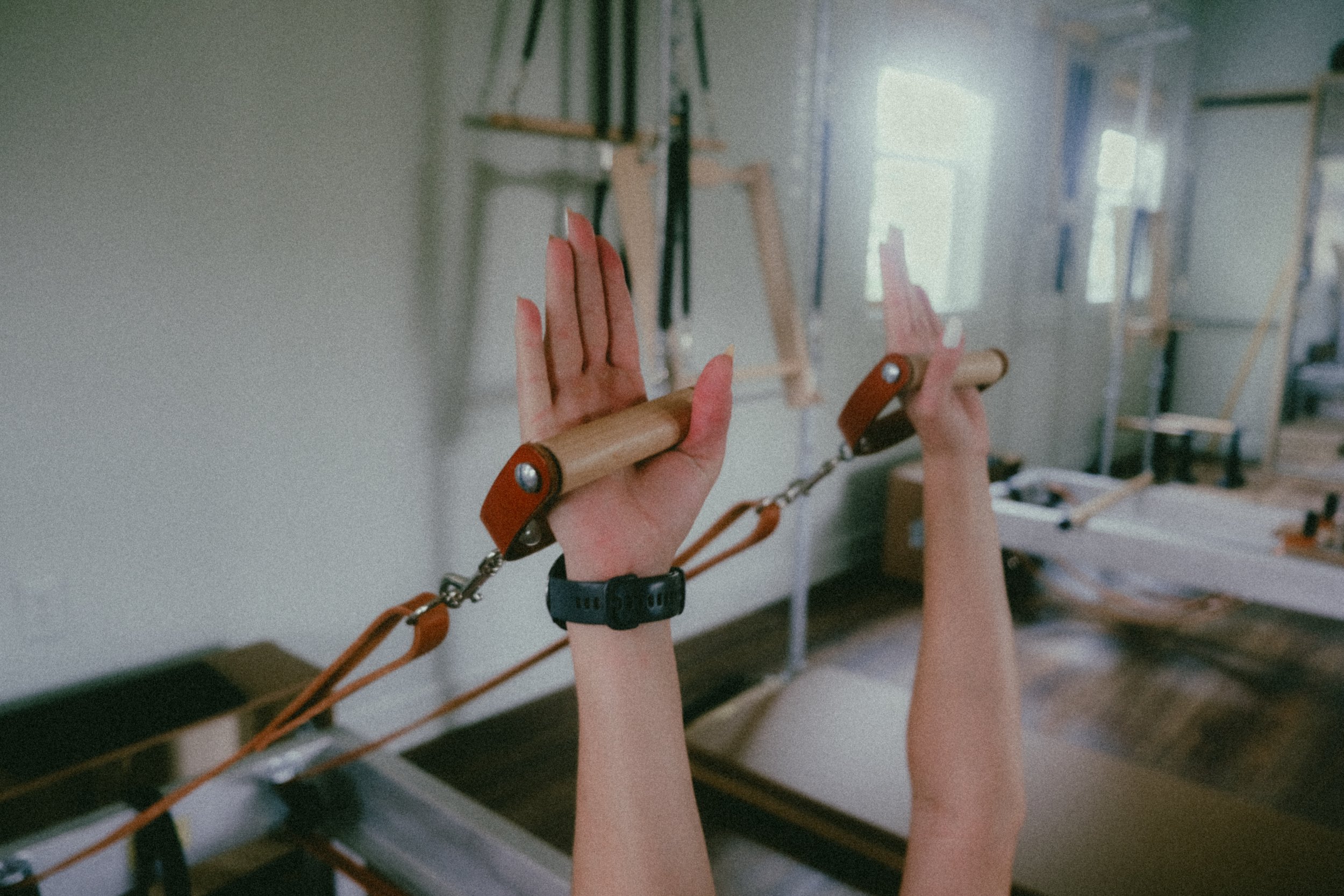 Image of a student at The Pilates Garage experiencing the difference using wooden handles for The Hundred makes on the reformer.