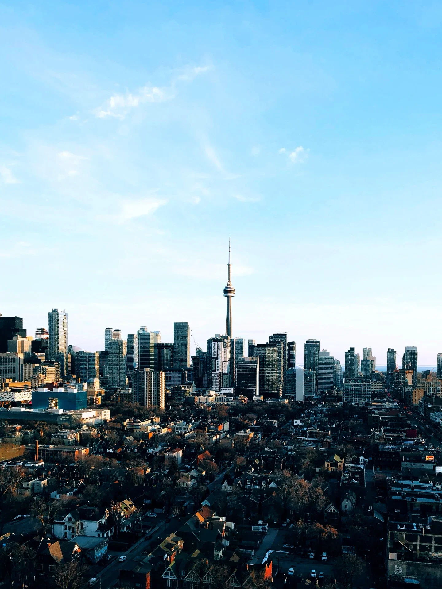 A city skyline with numerous tall skyscrapers and a prominent tower in the center, under a clear blue sky.