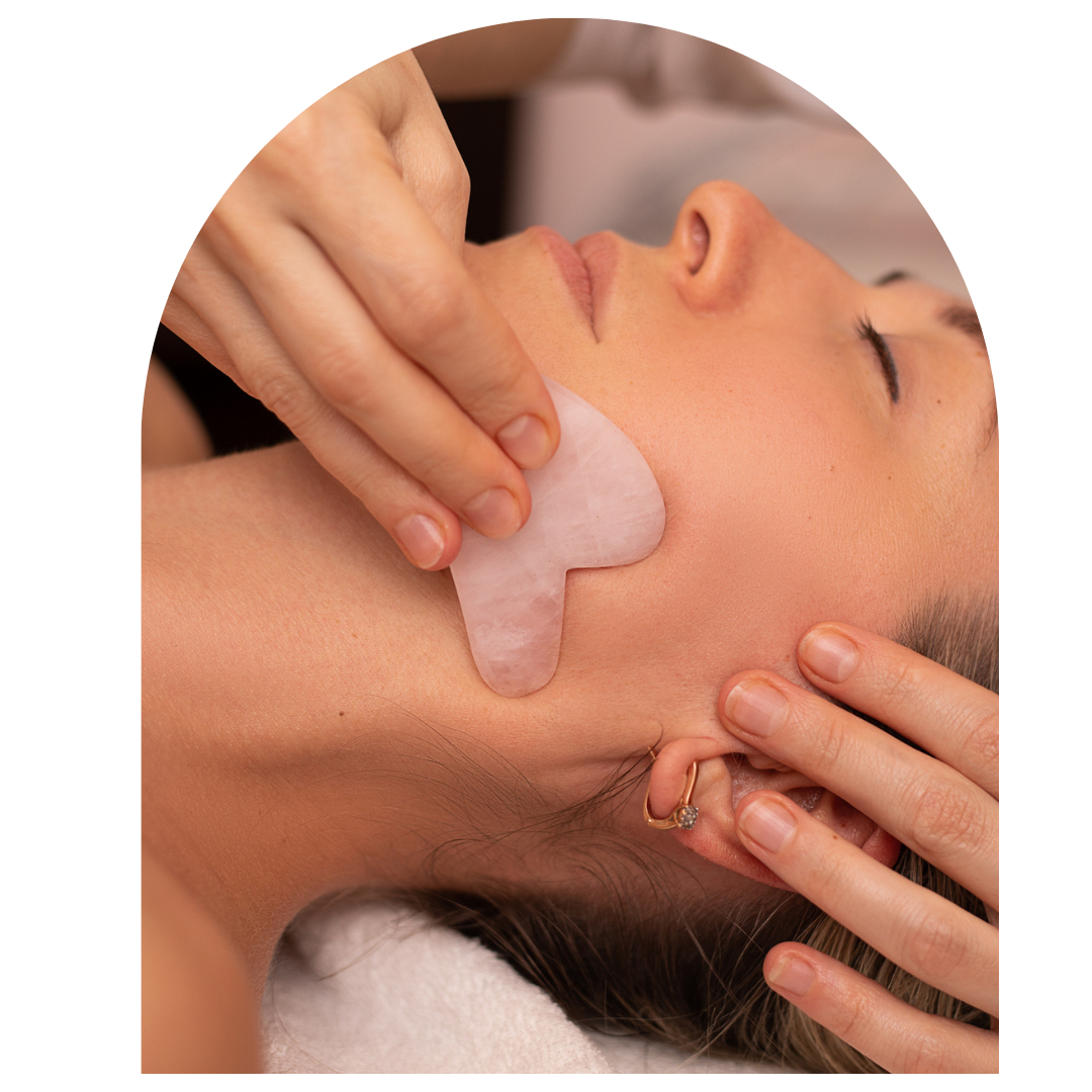 Close-up of a woman receiving a gentle facial gua sha massage using a rose quartz stone tool, promoting relaxation and circulation