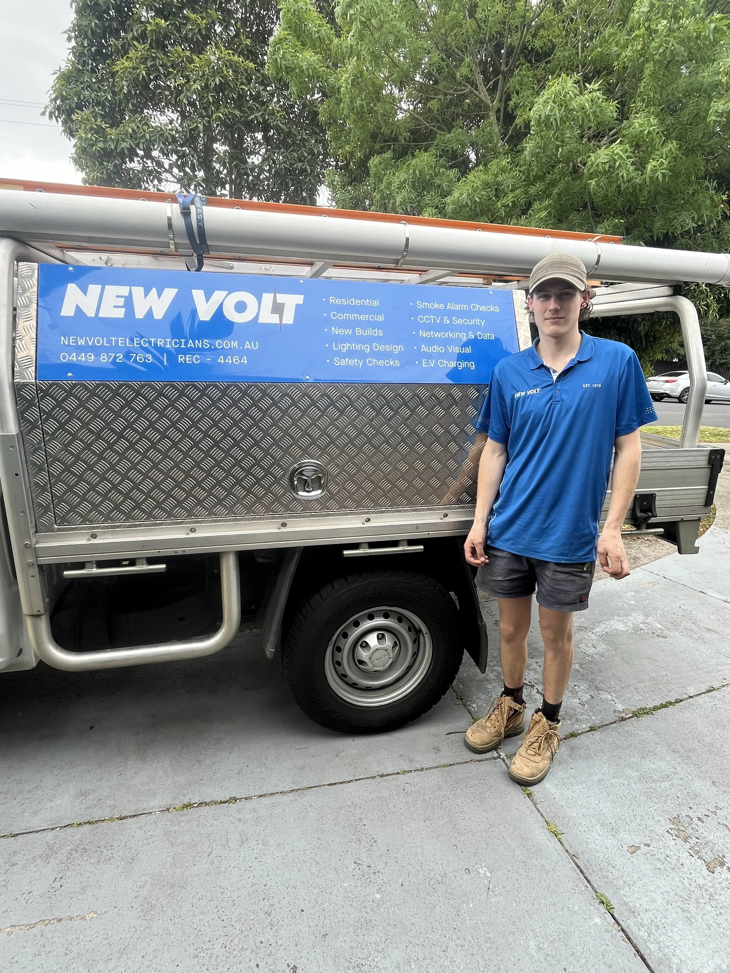 Person soldering wires in a wall opening during a repair or construction project, with tools and materials on the floor.