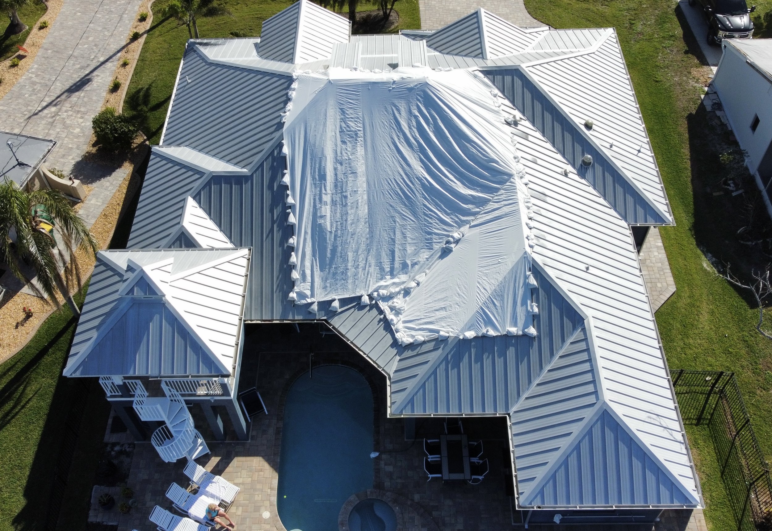 Metal roof with tarps in place mitigating damages by Hurricane Ian in Florida 2023