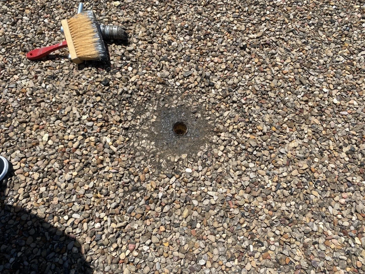 Photo of a core sample along with core tool on a built up gravel ballast roof system 