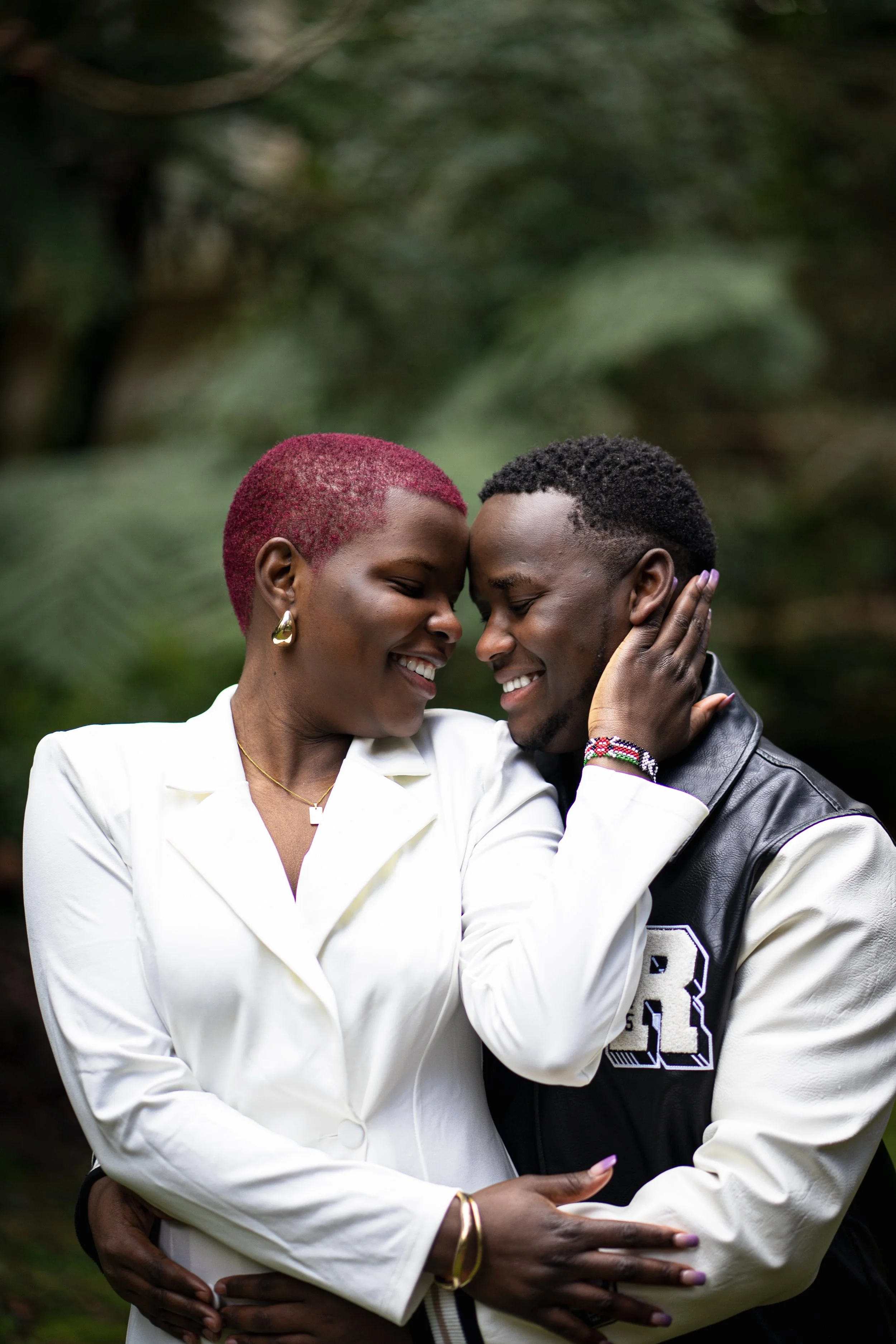 A couple in an outdoor natural setting, smiling and embracing each other closely.