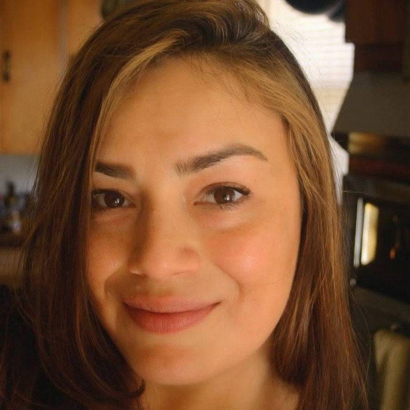 Close-up of a woman with light brown hair and a gentle smile in an indoor setting.