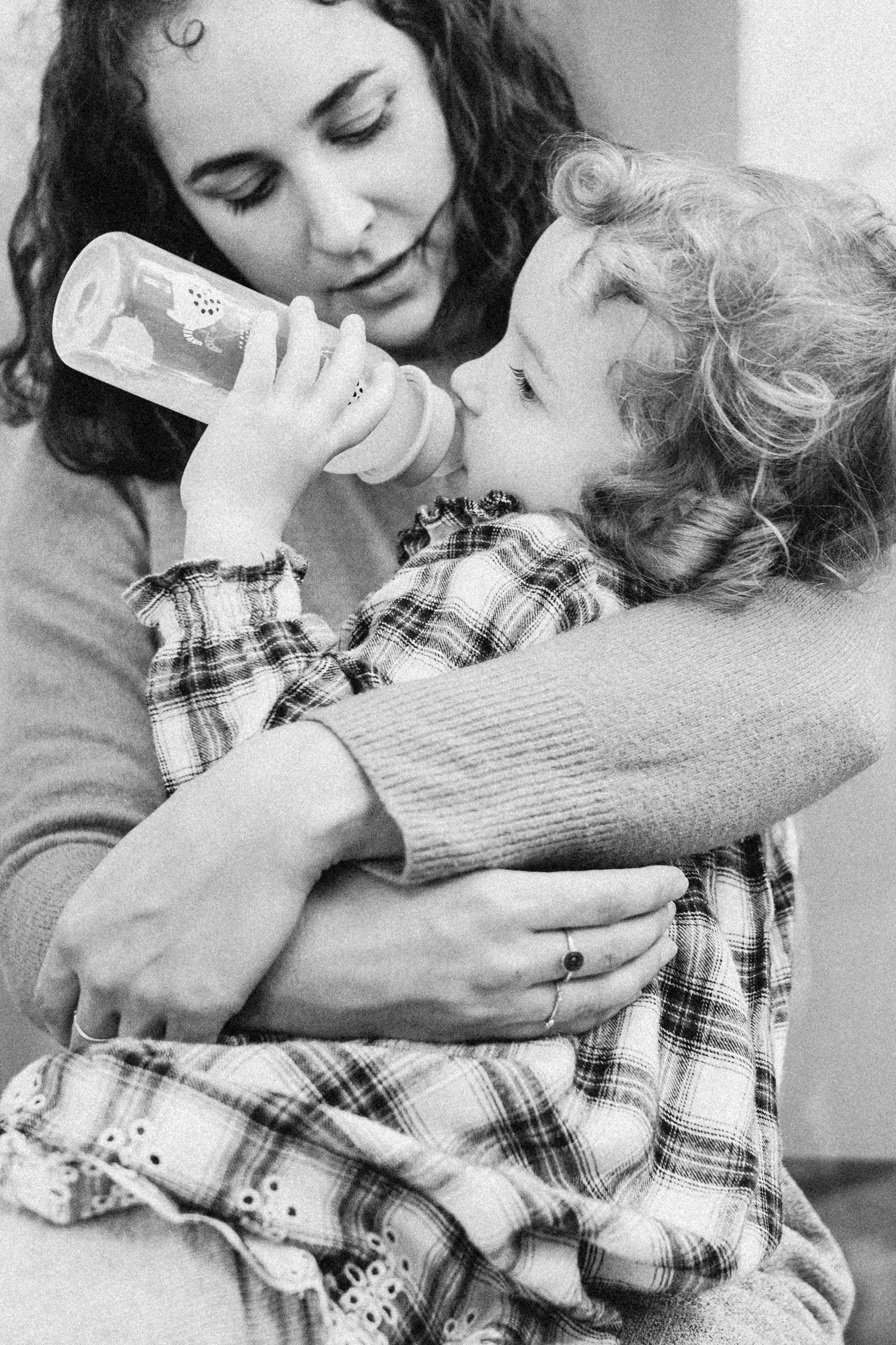 Eine junge Frau hält ein Kind im Arm, das ein Fläschchen trinkt.