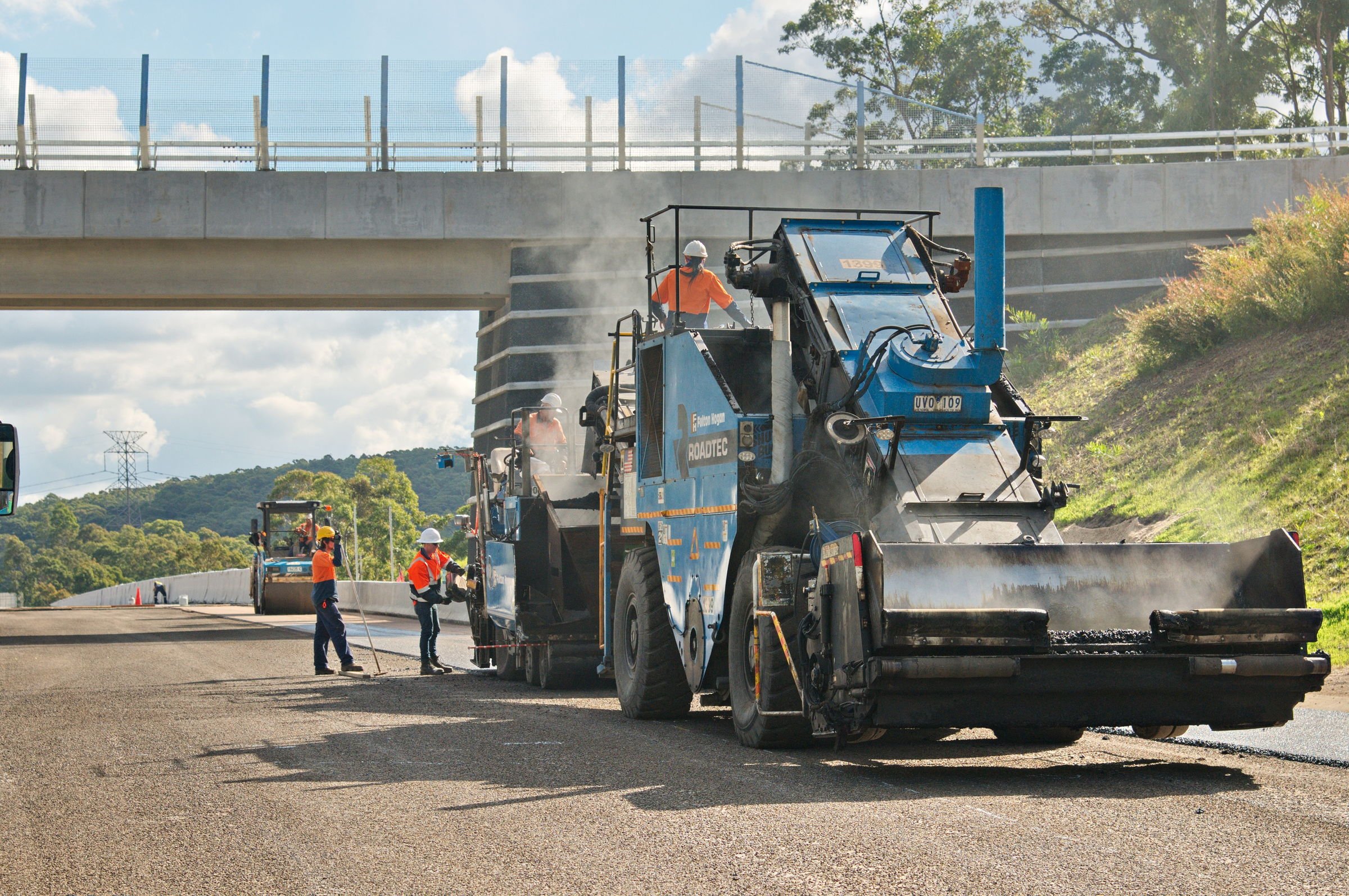 Asphalt paving crew working beneath a bridge on the Hunter Expressway