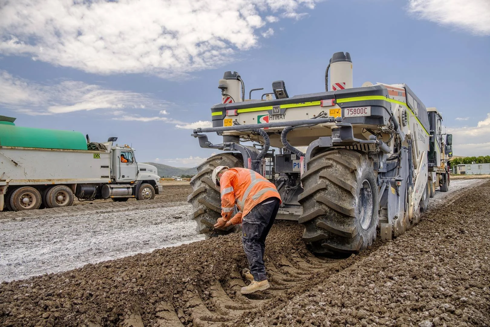 Worker beside a road stabiliser during civil construction works in NSW