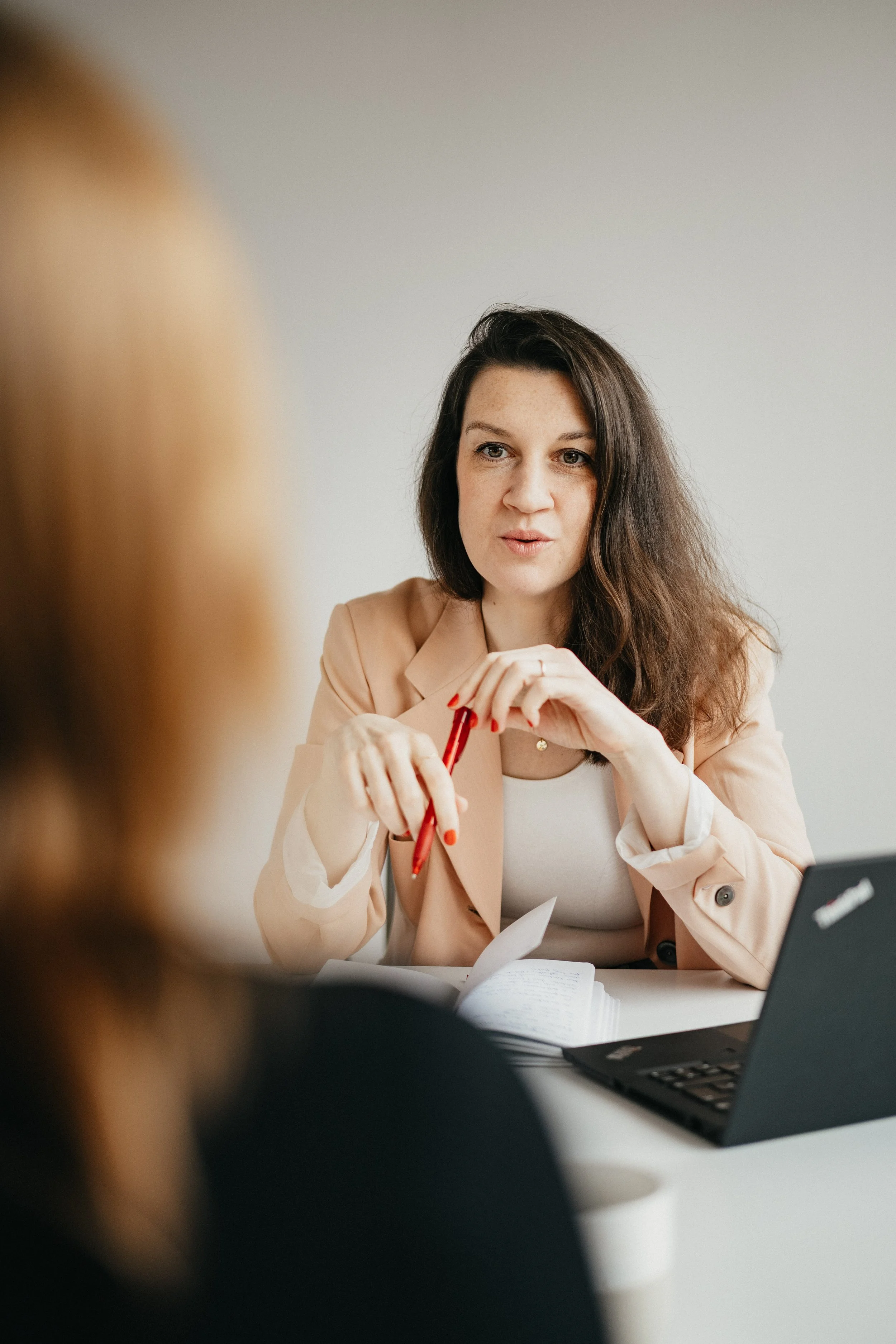 Zwei Frauen, eine in Nahaufnahme, in einem Gespräch am Tisch mit einem Laptop.