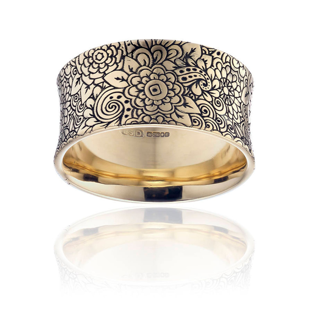 Gold eclipse ring engraved on the outside with a floral motif.