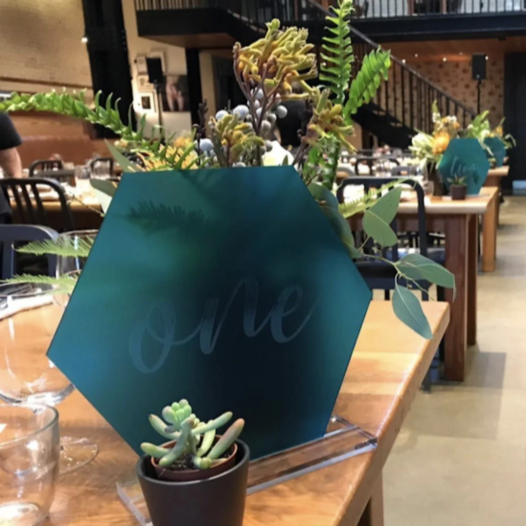 Table numbers created from laser-cut and engraved turquoise acrylic.