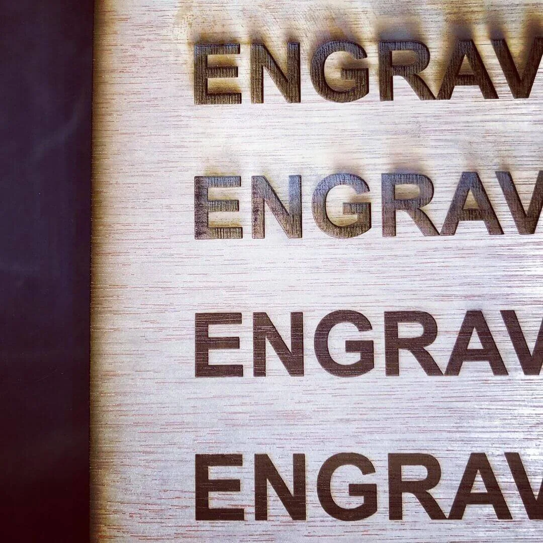 Close-up view of a wooden surface with the word 'ENGRAVE' engraved repeatedly.