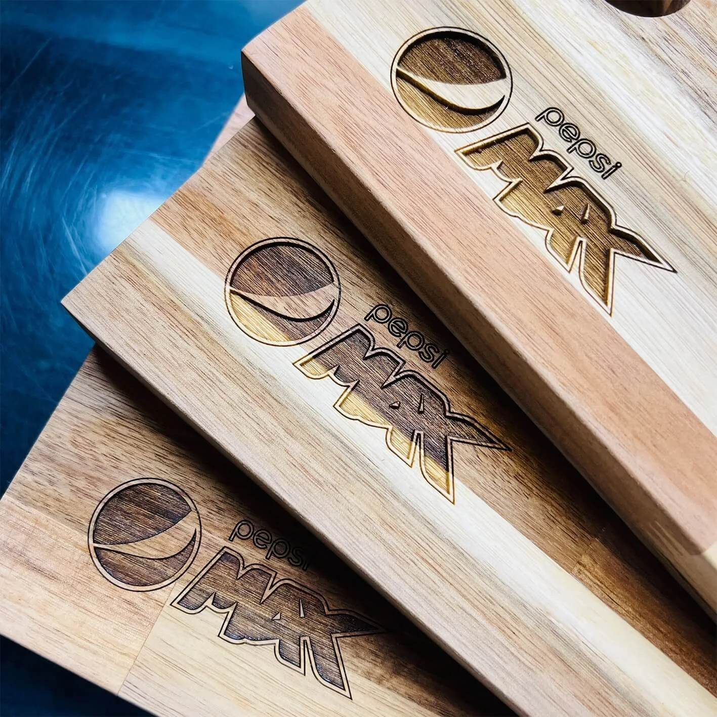Three stacked wooden chopping boards, each with the Pepsi logo and text engraved.