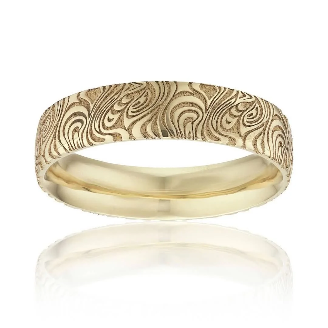 Gold wedding ring with an intricate engraved swirl pattern.