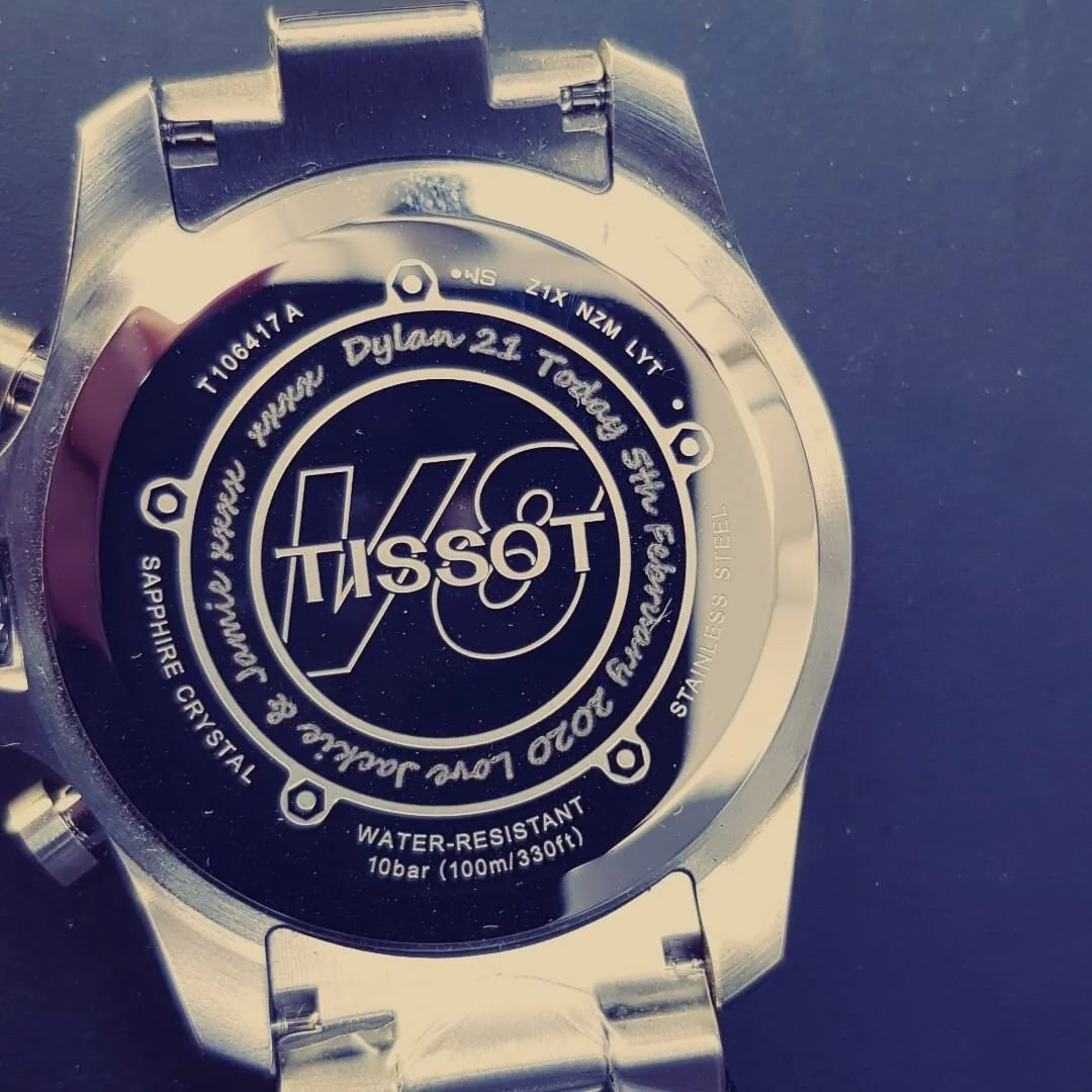 Back of a stainless steel Tissot watch that has been engraved.