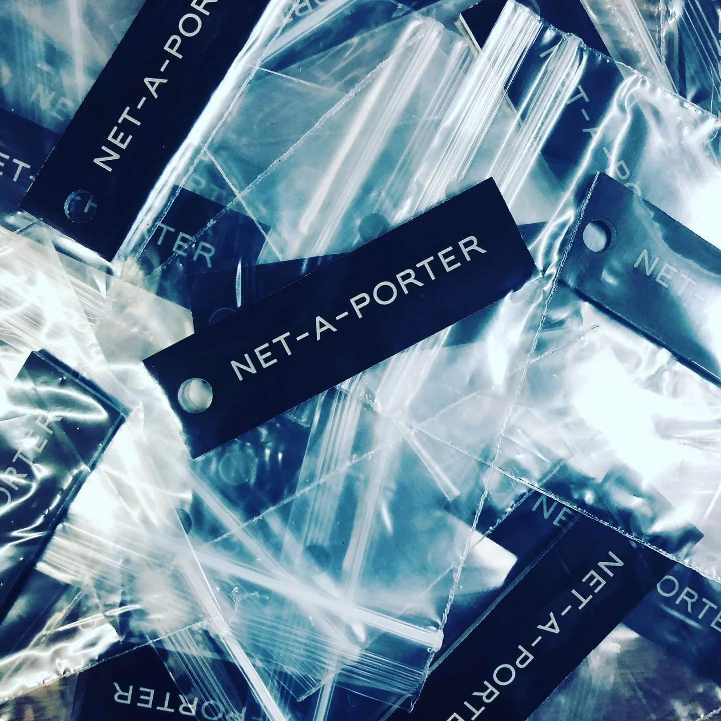 Multiple coated aluminium tags engraved with 'NETT-A-PORTER'.