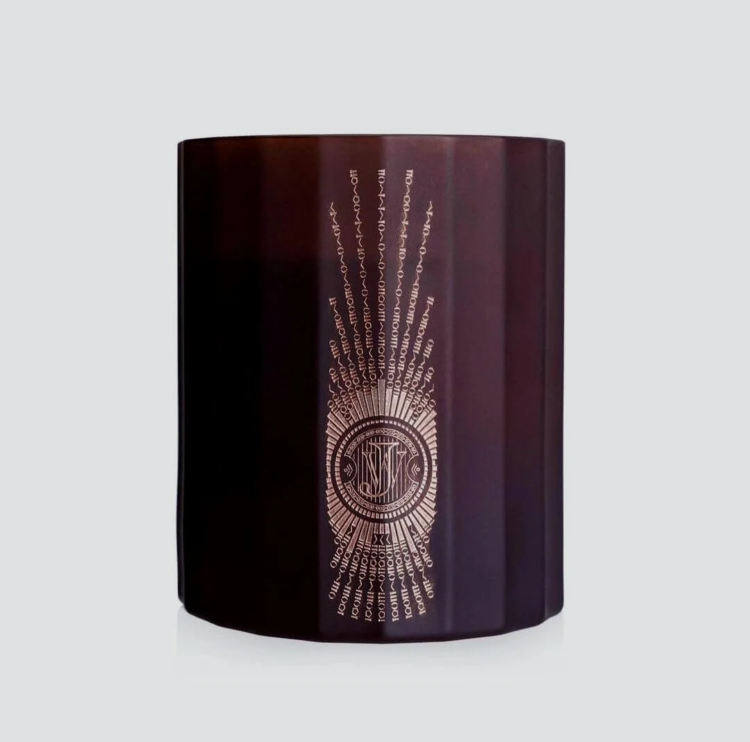 A dark bottle with a gold-engraved design and logo, displayed against a plain background.