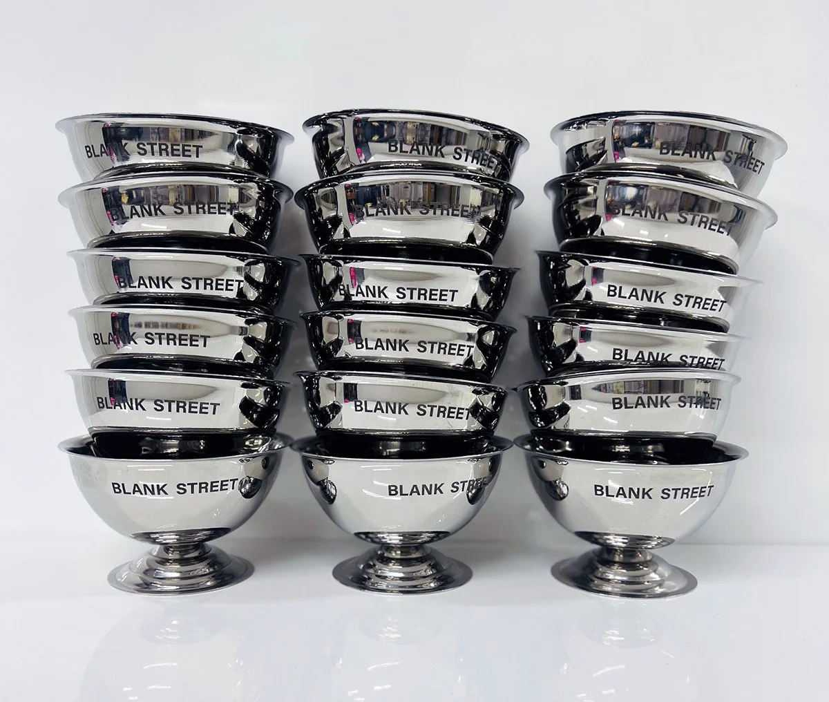Stacked ice cream bowls with the words "BLANK STREET" engraved on the side, arranged in three columns on a white surface.