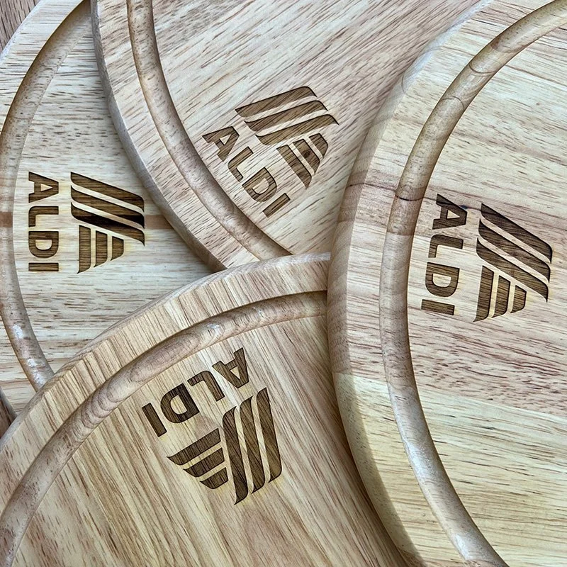 Several round wooden cutting boards stacked together, each engraved with the words "ALDI" and a stylized logo.