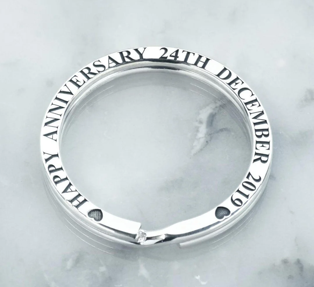 Silver key ring engraved with a celebratory message commemorating the 24th anniversary, reading 'HAPPY ANNIVERSARY 24TH DECEMBER 2019' and featuring small heart and circle decorative details.