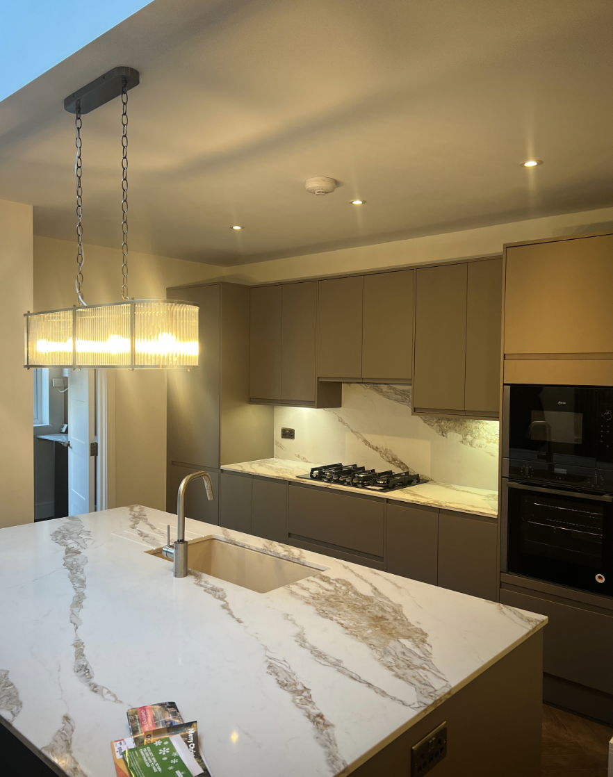 Modern kitchen renovation with marble island worktop, integrated appliances, handleless cabinets and warm ambient lighting