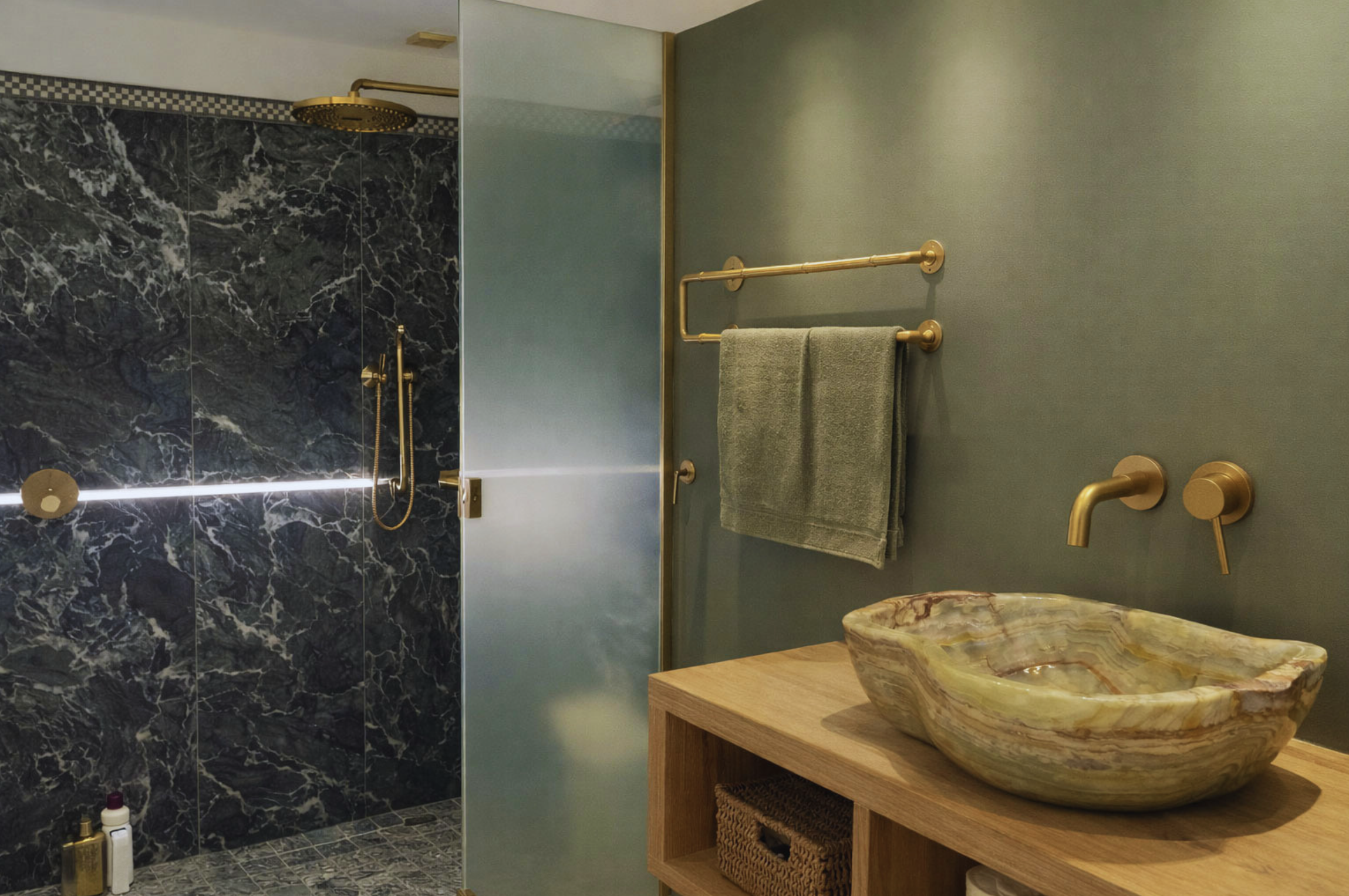 Luxury modern bathroom with marble walk-in shower, brushed brass fixtures, stone basin sink and minimalist vanity design