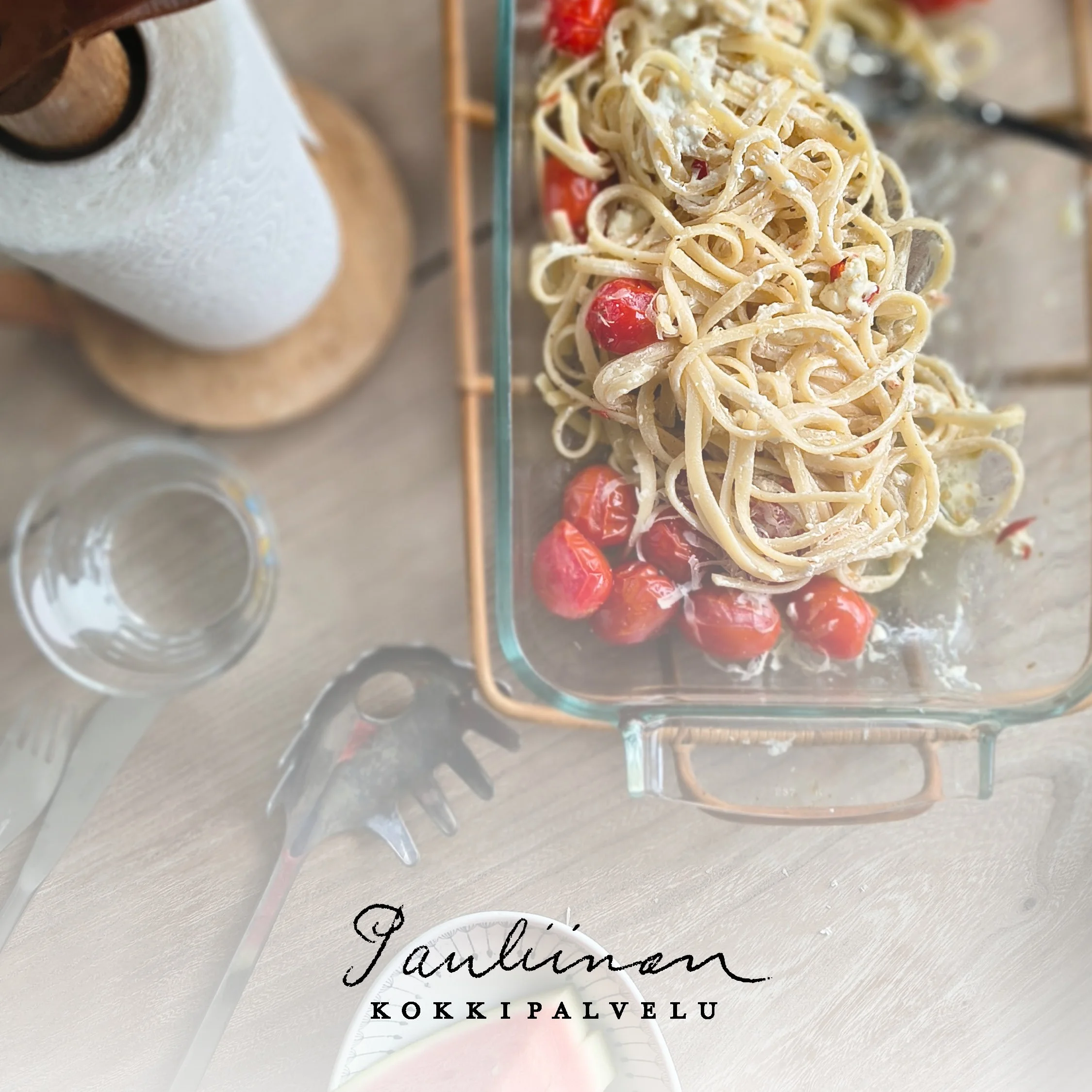 Kuvassa kaunis puinen talouspaperirulla ja lasisessa vuoassa paahdettuja kirsikkatomaatteja ja fetaa sekä Linguine-pastaa