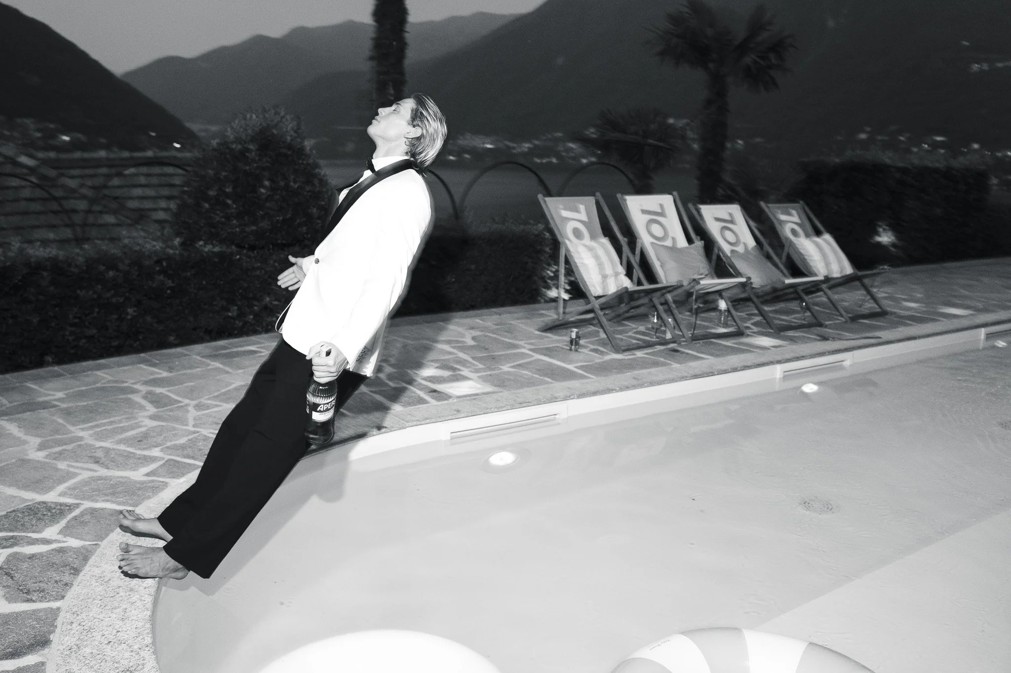luxury wedding photography with a grom jumping in the pool on lake como