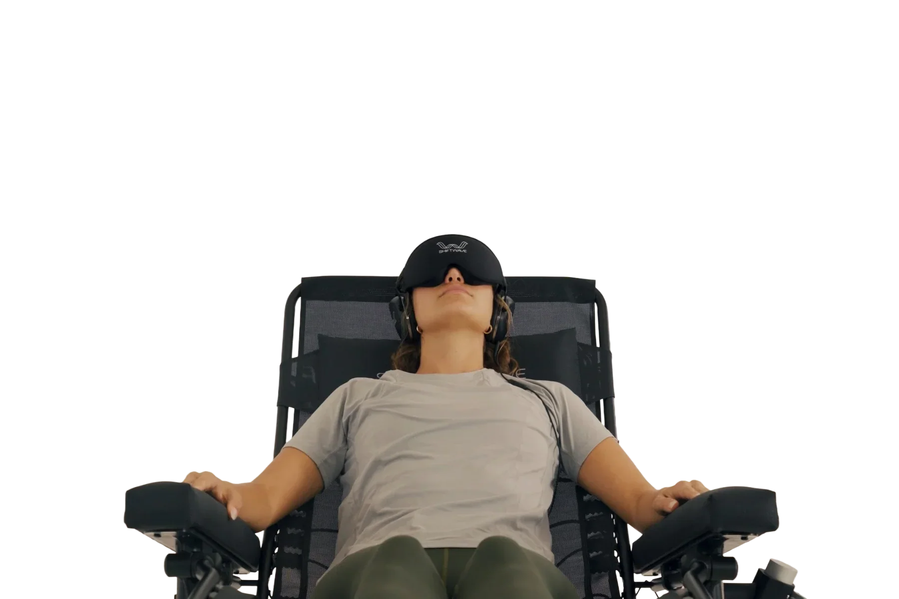 A woman is lying back on a reclining chair while wearing a virtual reality headset. She has her arms resting on the armrests and her eyes are covered by the VR headset.