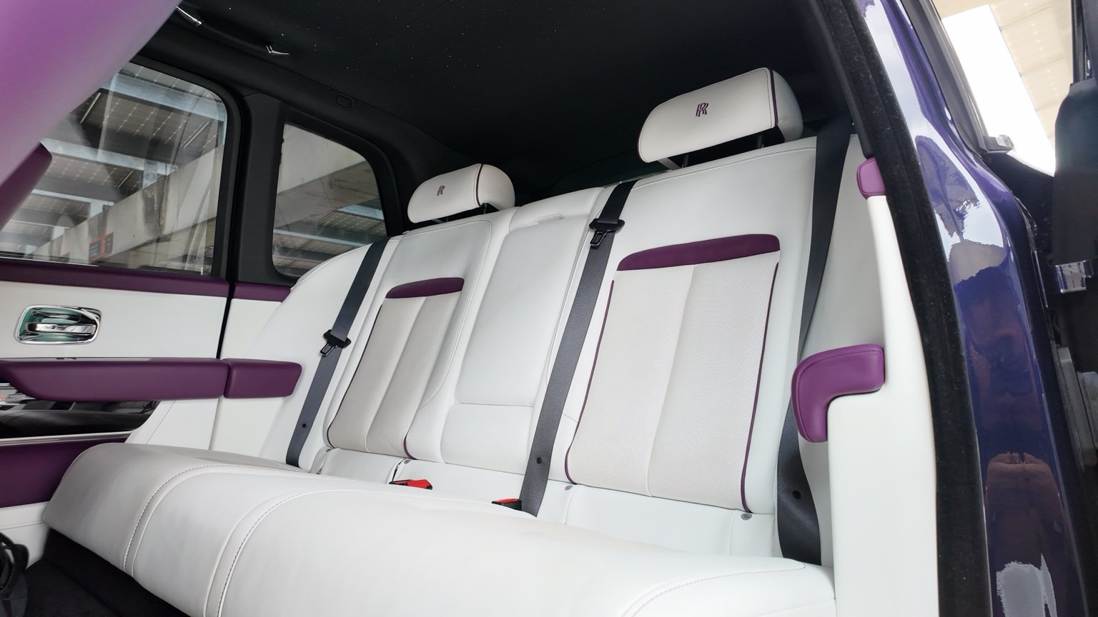 Rear passenger seating in Rolls Royce Cullinan featuring white leather and custom purple accents