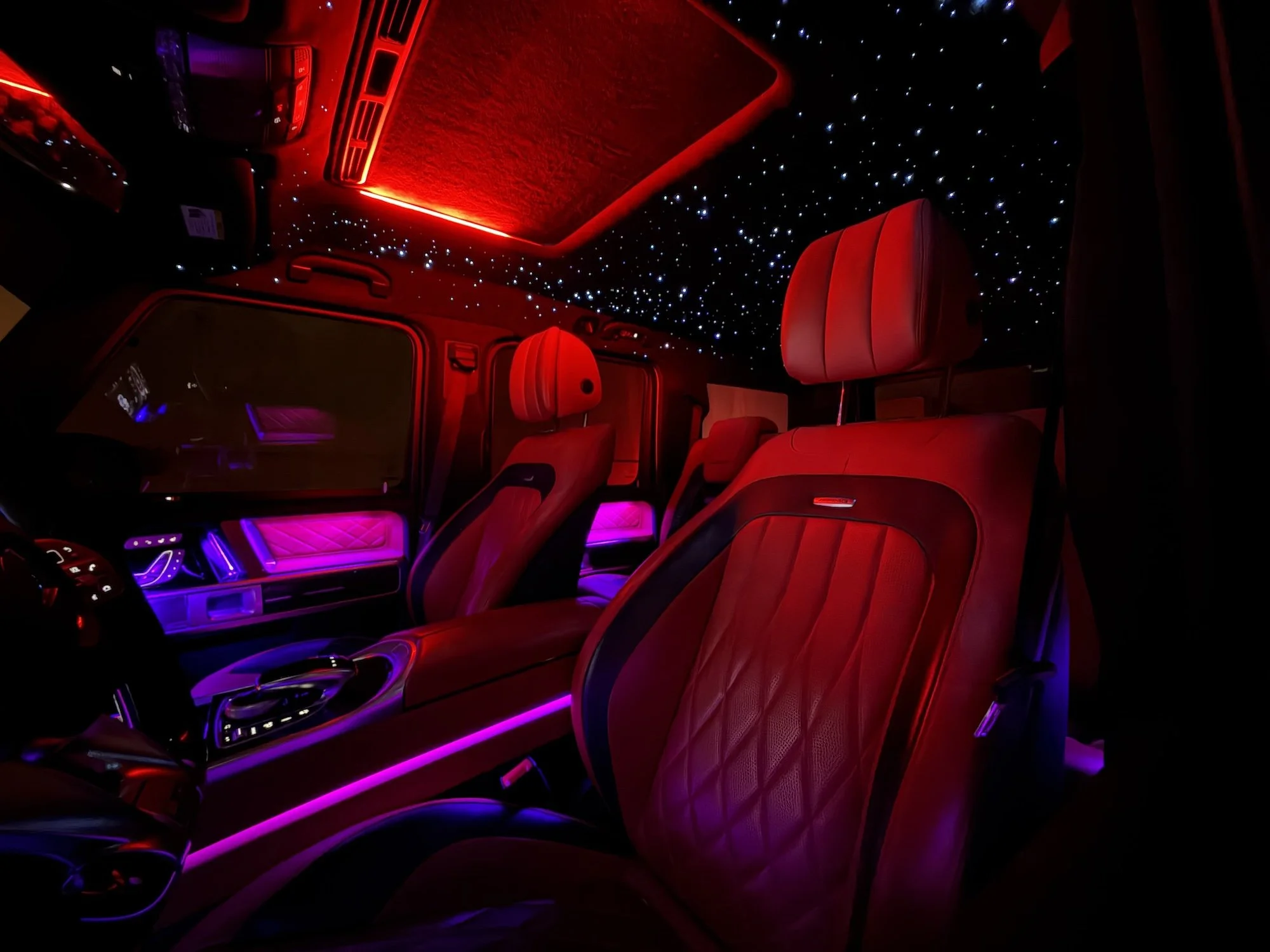 Luxury Mercedes G-Wagon interior featuring red leather seats, ambient lighting and a custom starlight roof