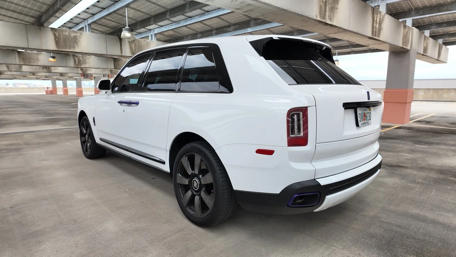 Rear exterior view of white Rolls Royce Cullinan luxury SUV rental in Tampa Florida