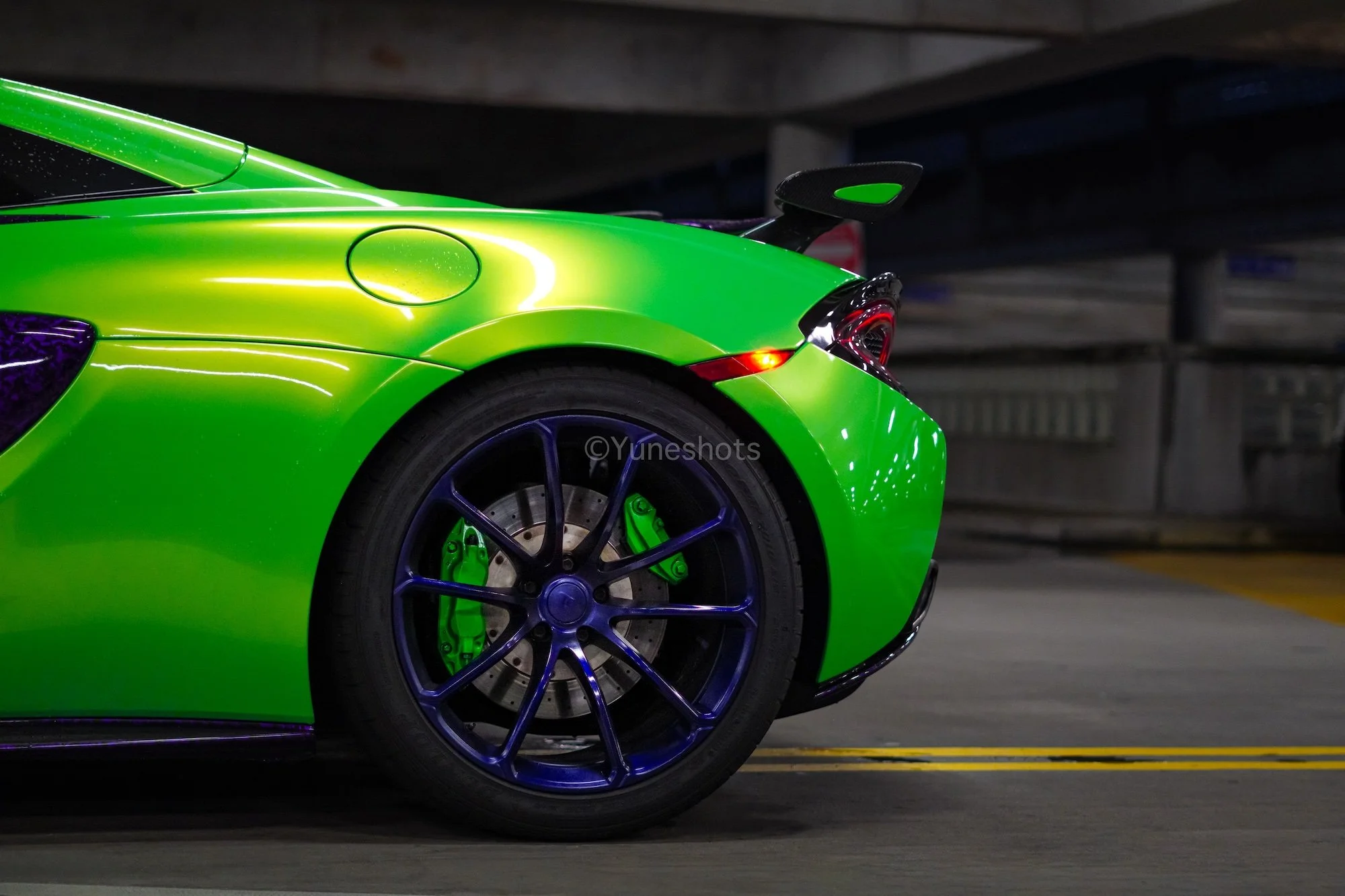Close-up of the custom purple wheel and forged carbon fiber accents on the green 2020 McLaren 570S Spyder.