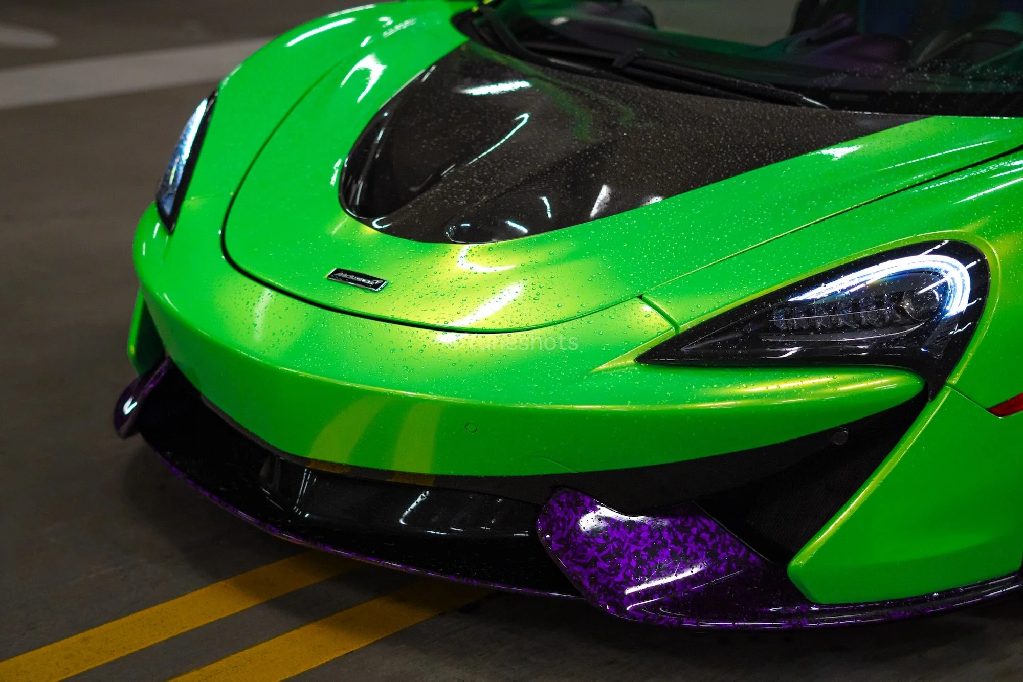 Close-up of the custom green 2020 McLaren 570S Spyder featuring purple forged carbon fiber front splitter and exposed carbon fiber hood.