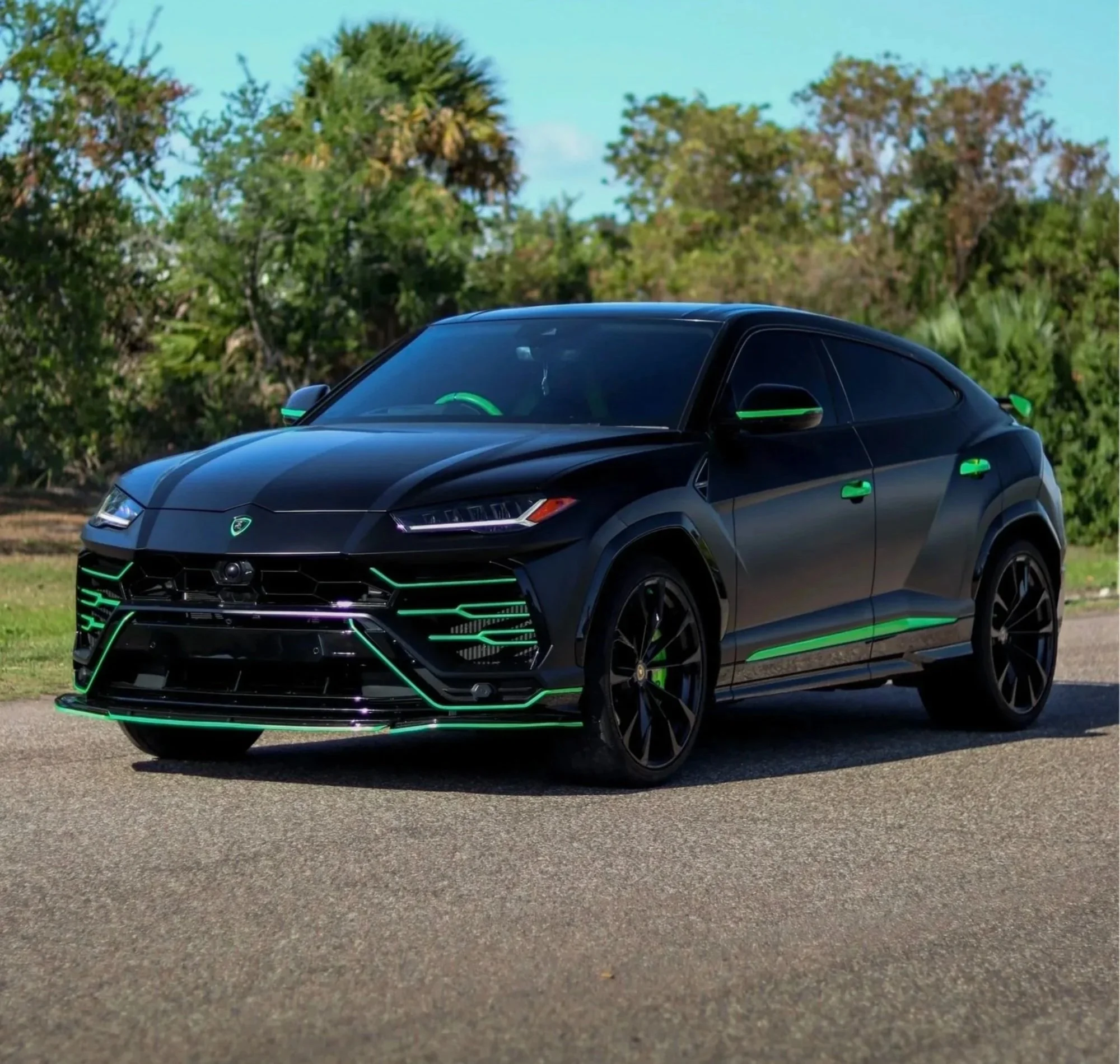 Front angle view of a satin black 2022 Lamborghini Urus with black carbon fiber hood, parked in front of a modern industrial building in Tampa, Florida — luxury exotic SUV rental