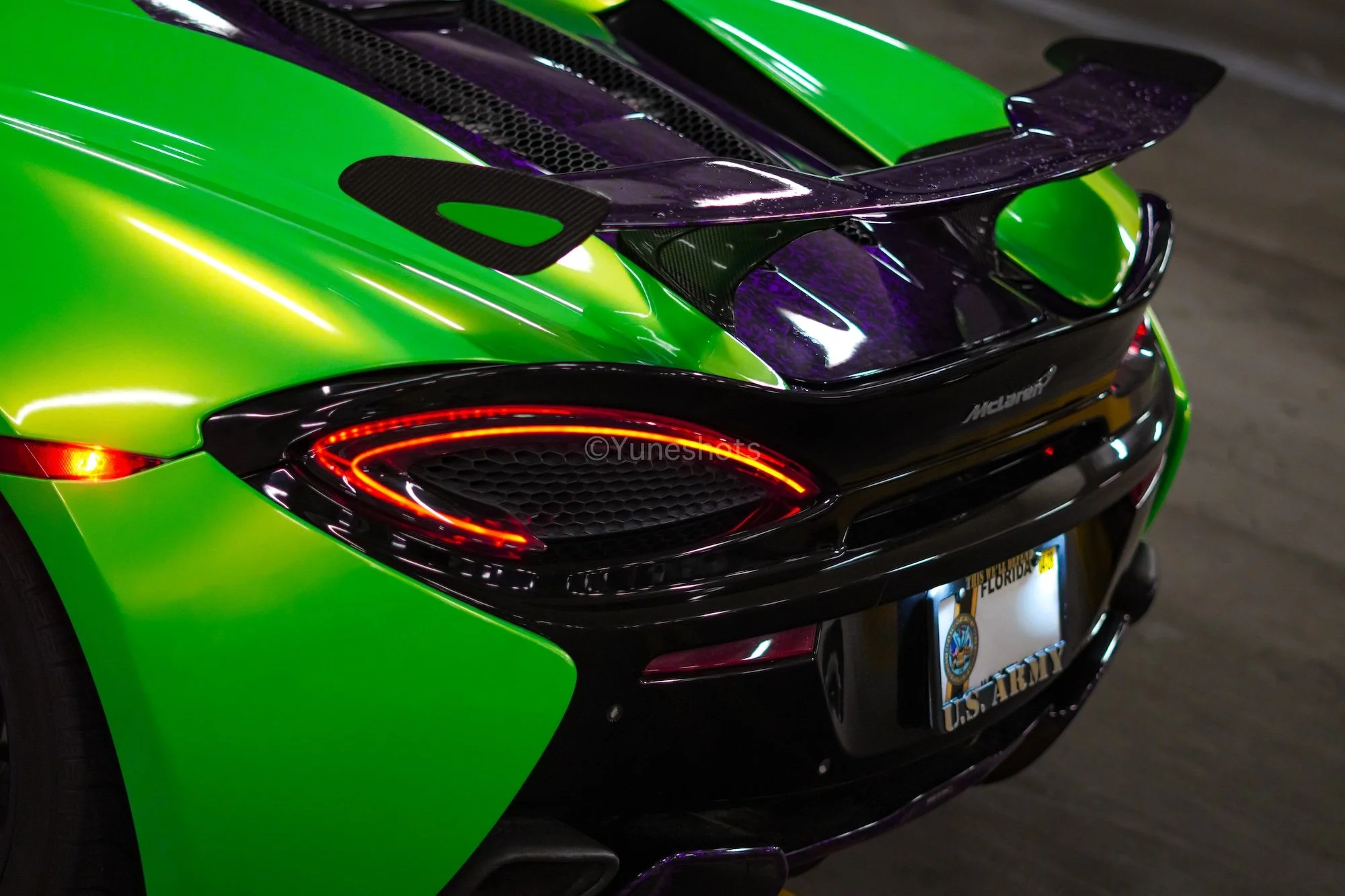 Rear quarter view of the custom green 2020 McLaren 570S Spyder showcasing purple forged carbon fiber accents and aerodynamic styling.