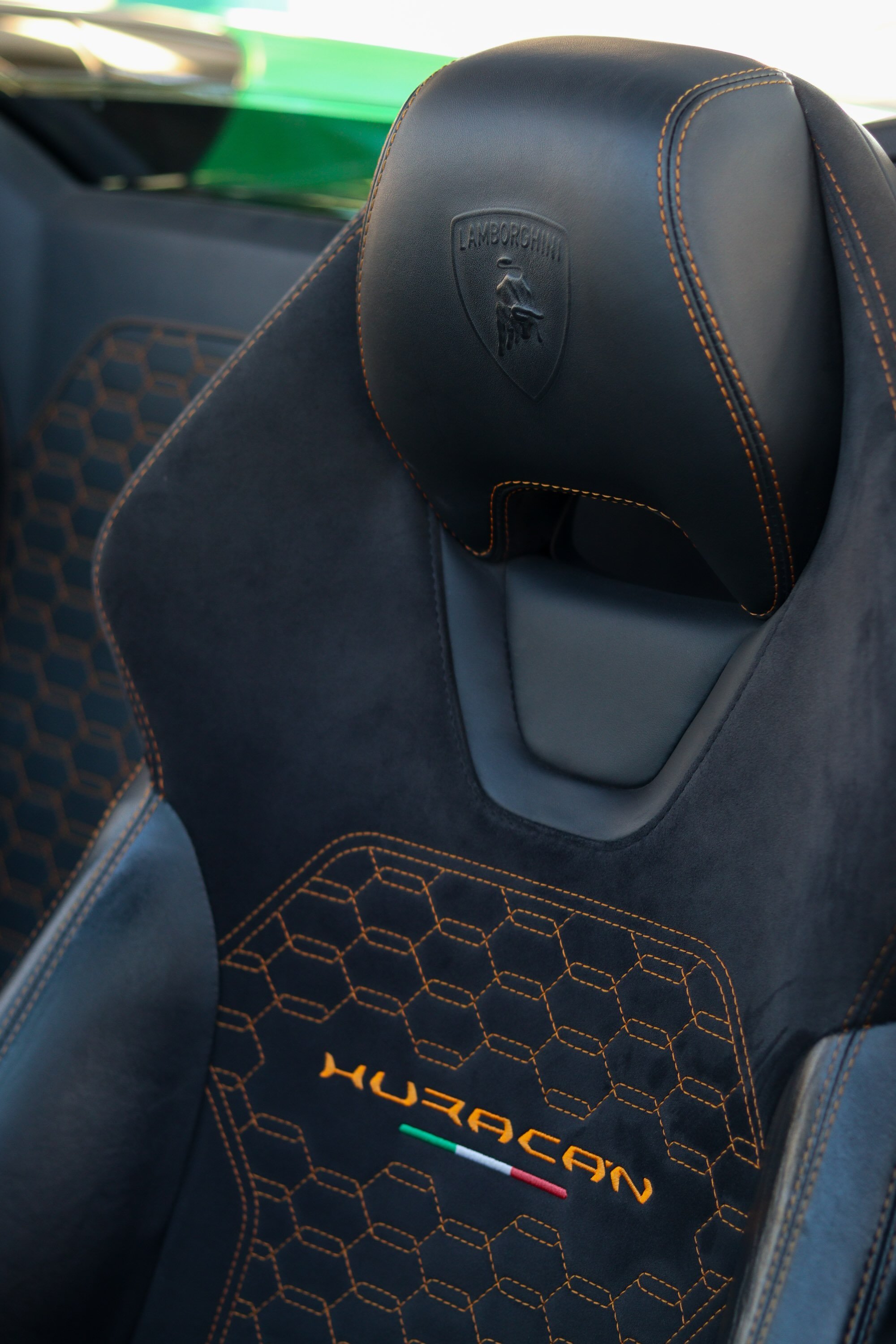 Interior seat detail of green 2019 Lamborghini Huracan Spyder rental in Tampa featuring Huracan stitching and Italian flag accent.